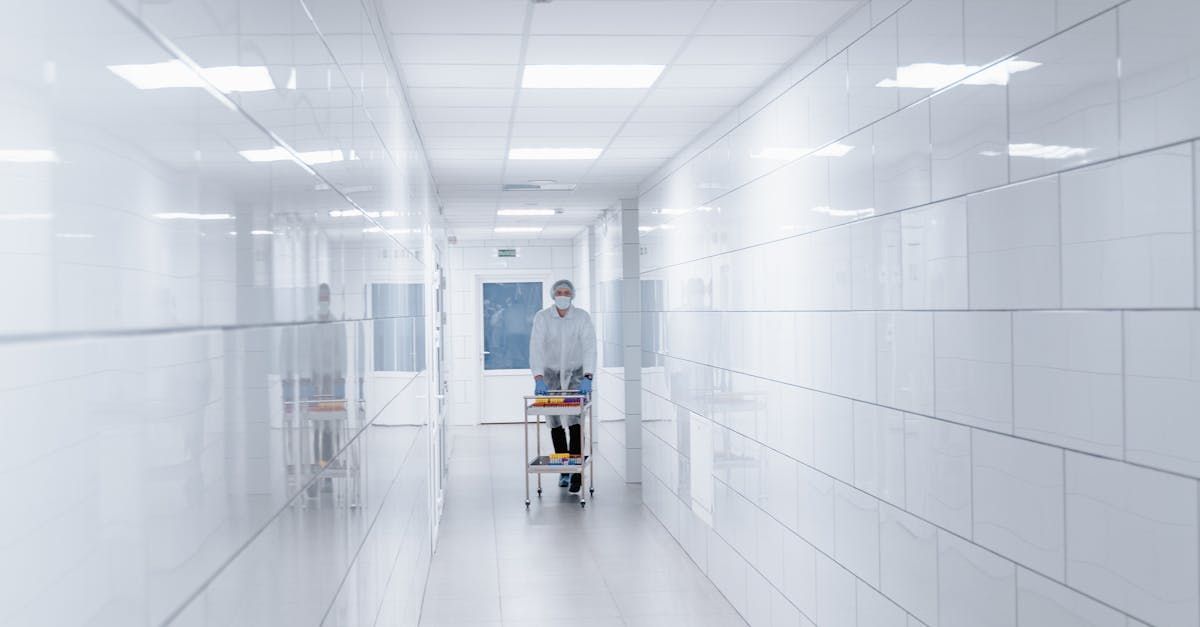 A man in a lab coat is pushing a cart down a hallway.