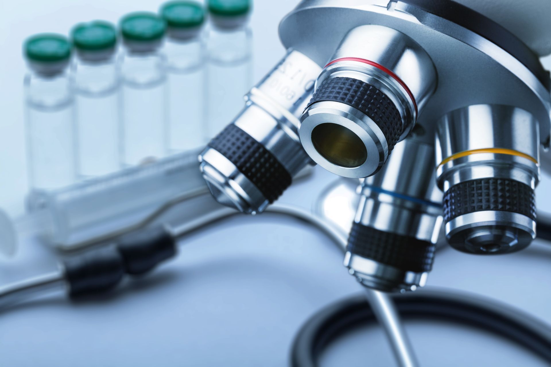 A close up of a microscope with bottles in the background