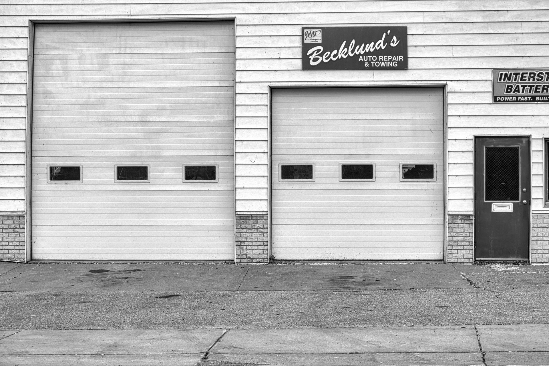 Exterior of auto repair shop with two garage doors and a door.