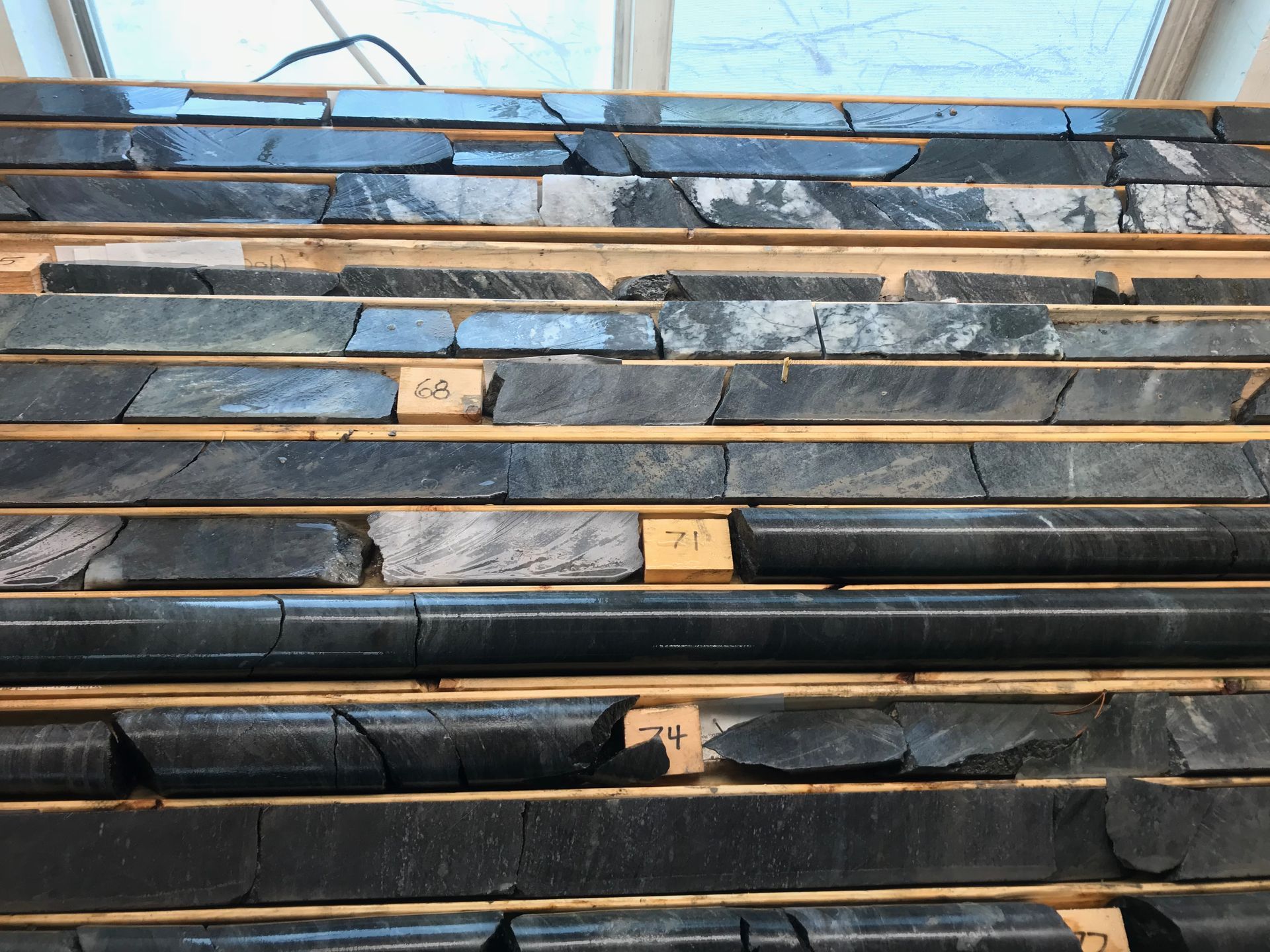 Three people shaking hands at a table, likely after a deal. Light-filled room with bookshelves.