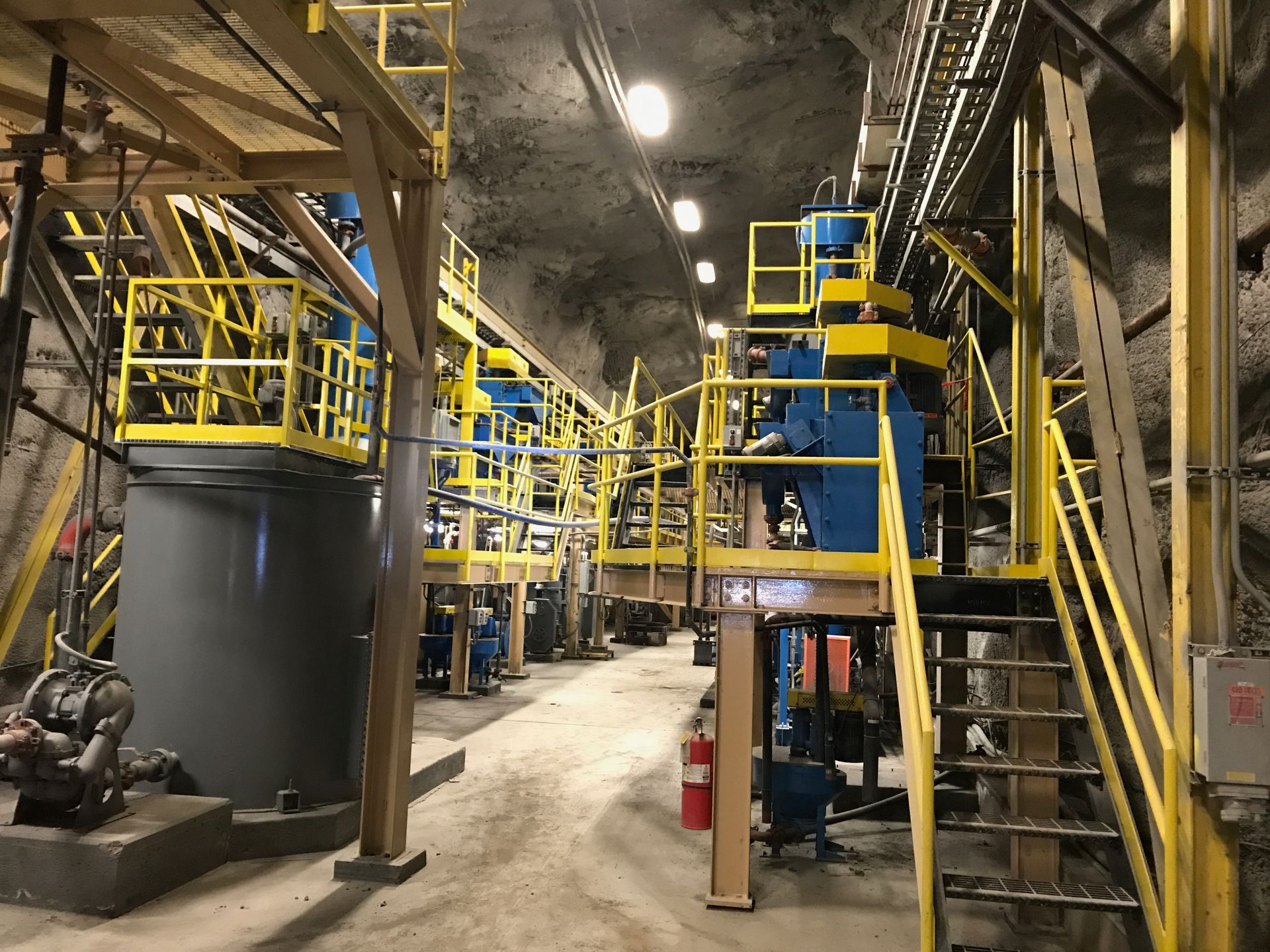 Three people in suits shaking hands in an office, window in the background.