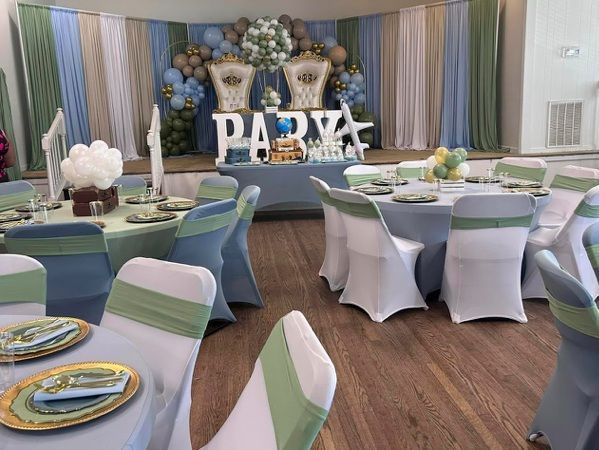 Baby shower: blue, green, and gold decor with chairs and tables set for guests.