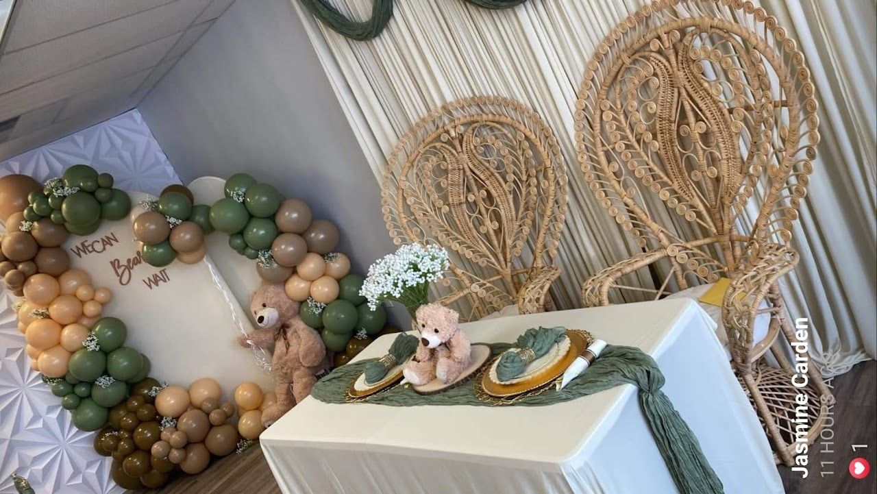 Baby shower decorations with balloons and teddy bears in neutral colors.