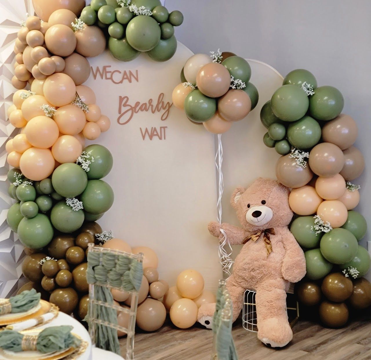 Baby shower backdrop: balloons in green, tan, and brown with a teddy bear, saying 