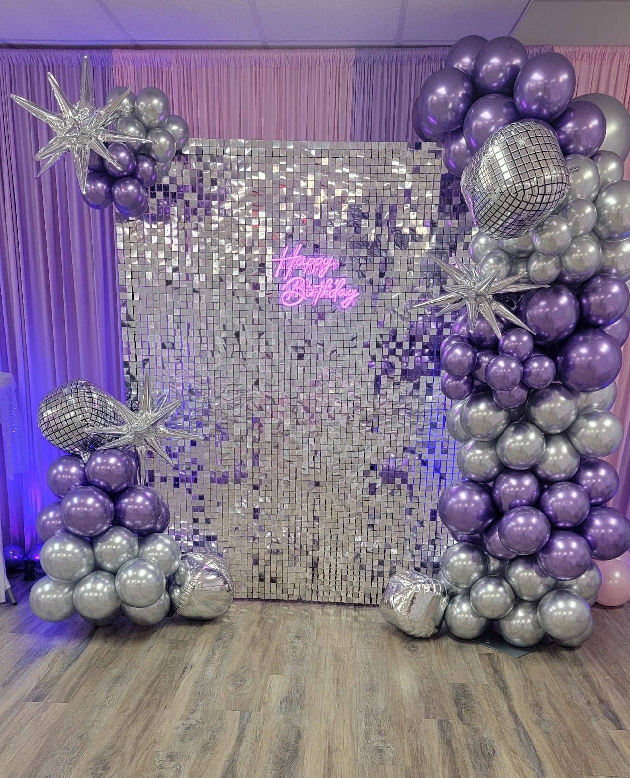 Party backdrop with silver and purple balloons, disco ball accents, and a silver backdrop.