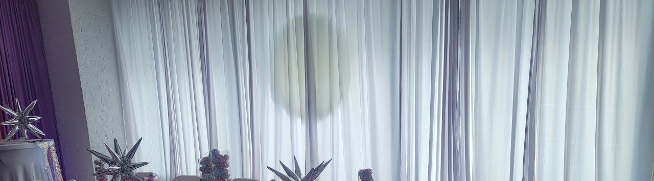 Interior scene with sheer curtains, plants and purple decor.