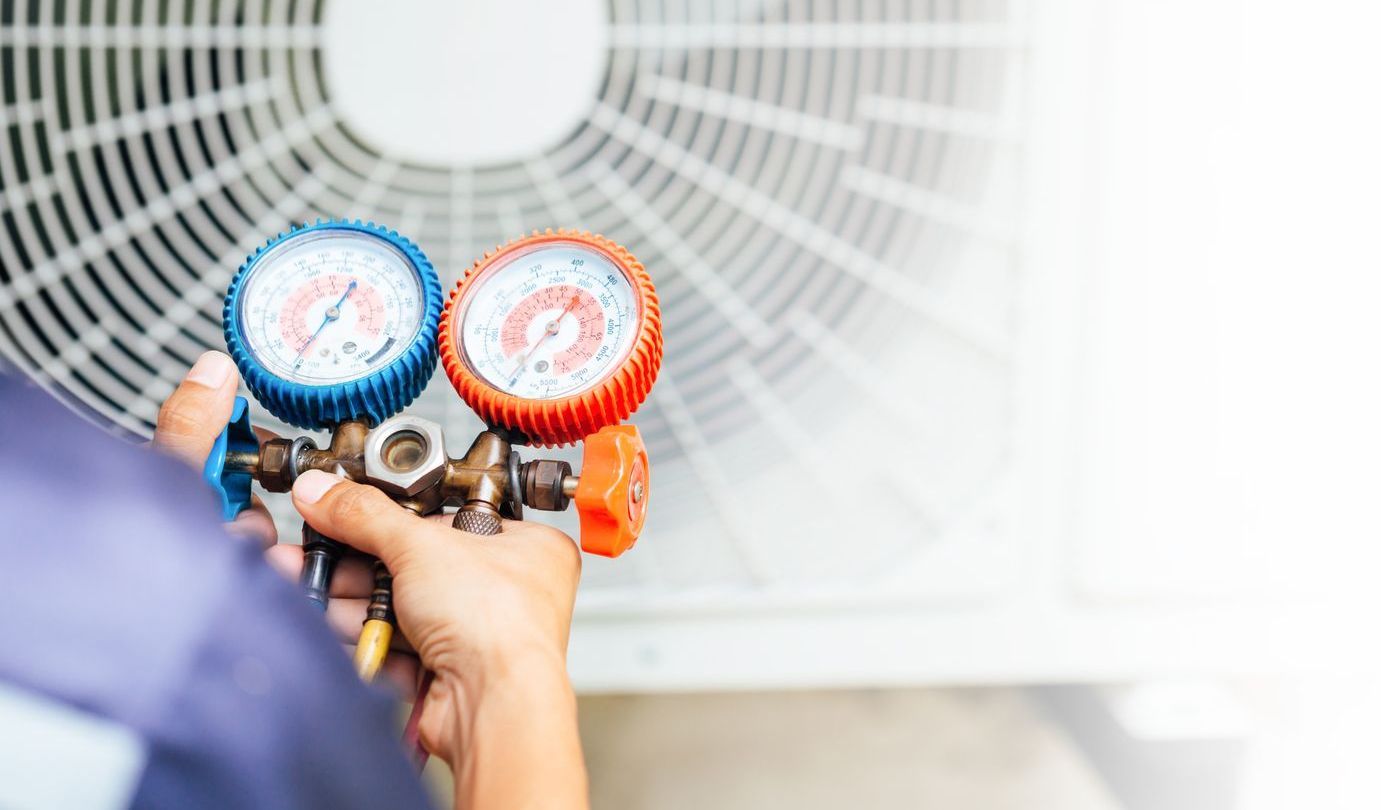 A man is working on an air conditioner outside of a house.