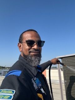 A large building with a lot of air conditioners on it is sitting on top of a gravel lot.