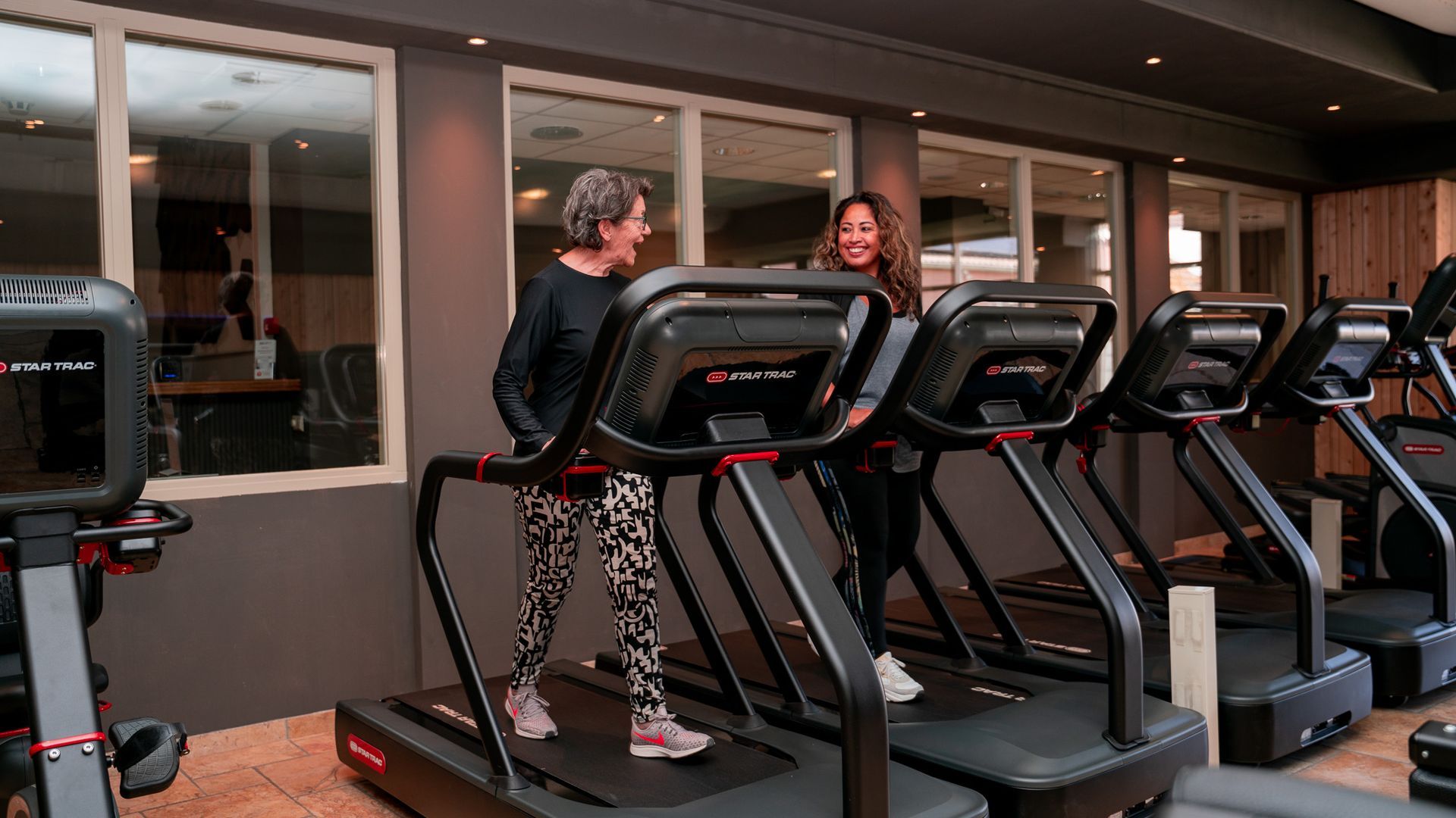 Twee vrouwen lopen op een loopband in een sportschool.
