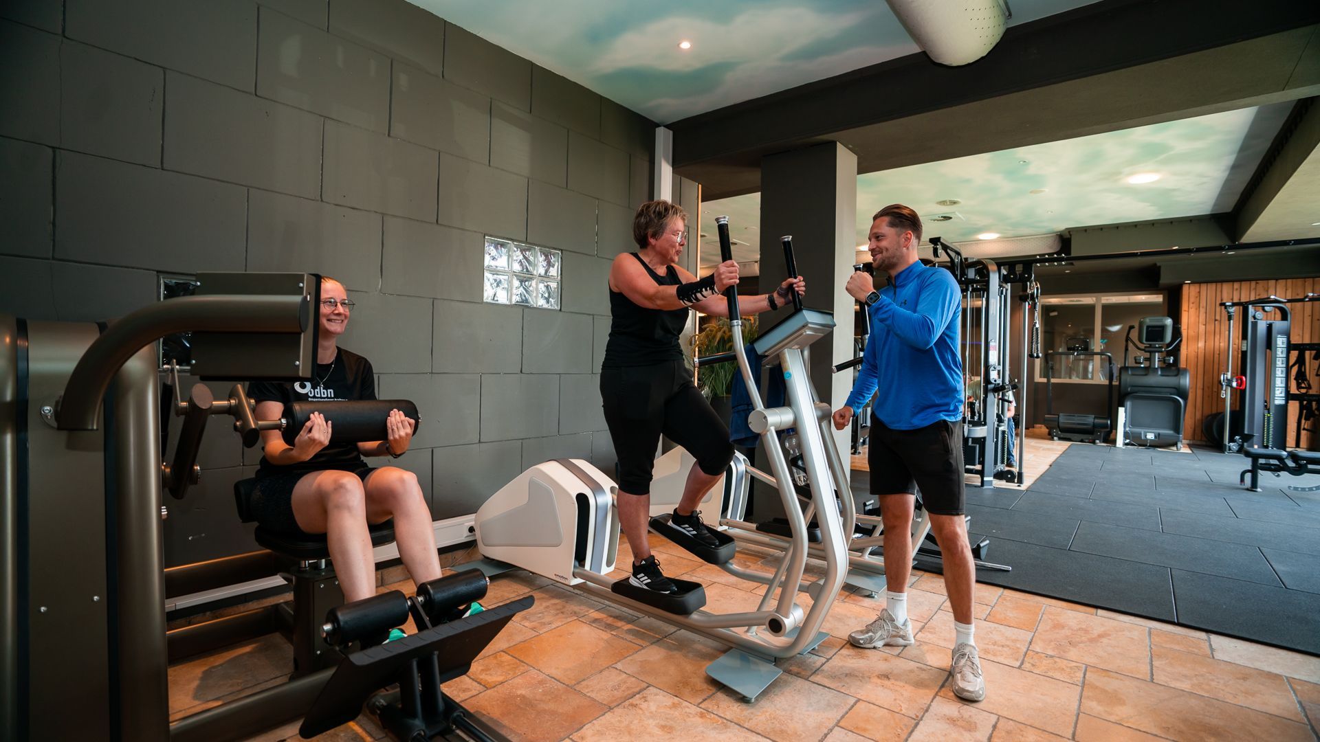 Twee vrouwen fietsen op hometrainers in een sportschool.
