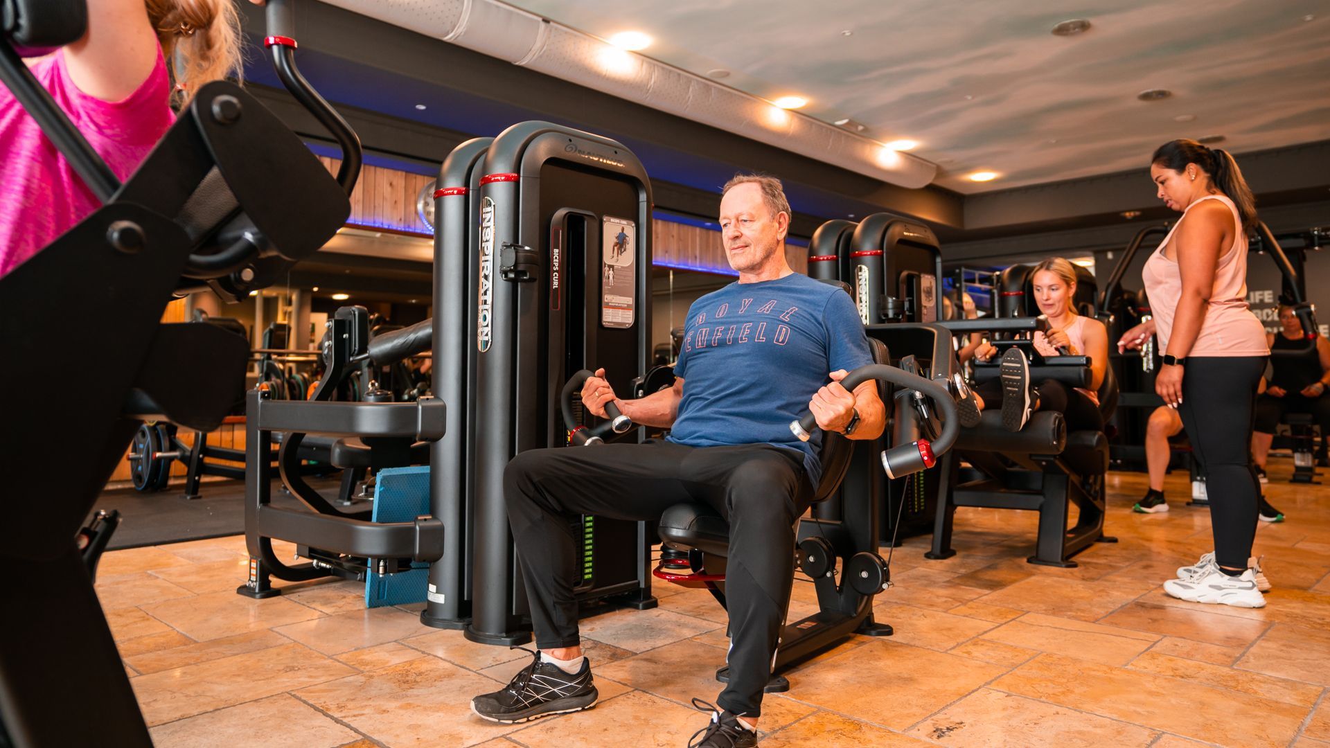 Een man helpt een andere man met het tillen van halters in een sportschool.