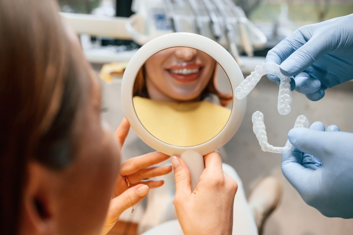 A dentist is holding a tooth color chart in front of a woman 's mouth.
