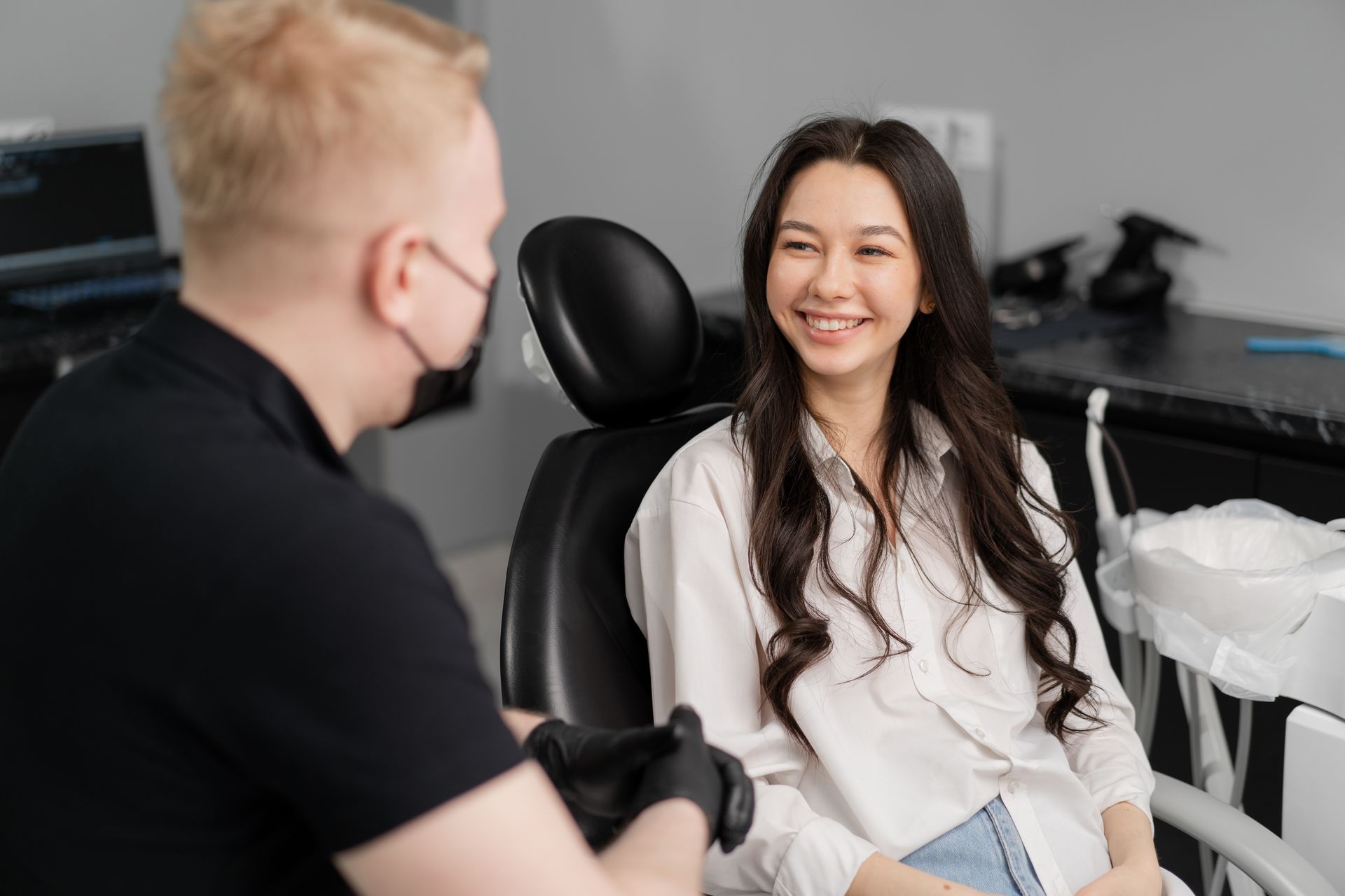 A woman is sitting in a dental chair talking to a dentist.