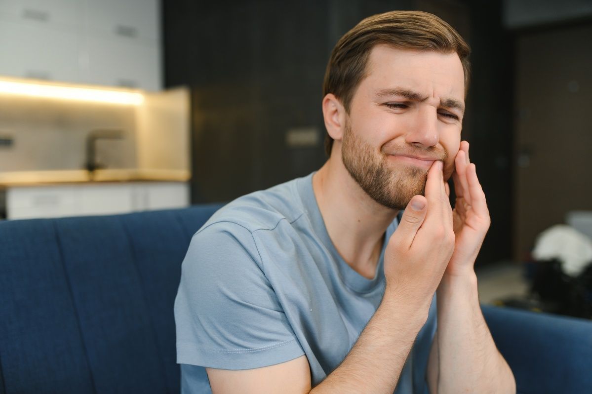 A woman is holding her face in pain because of a toothache.