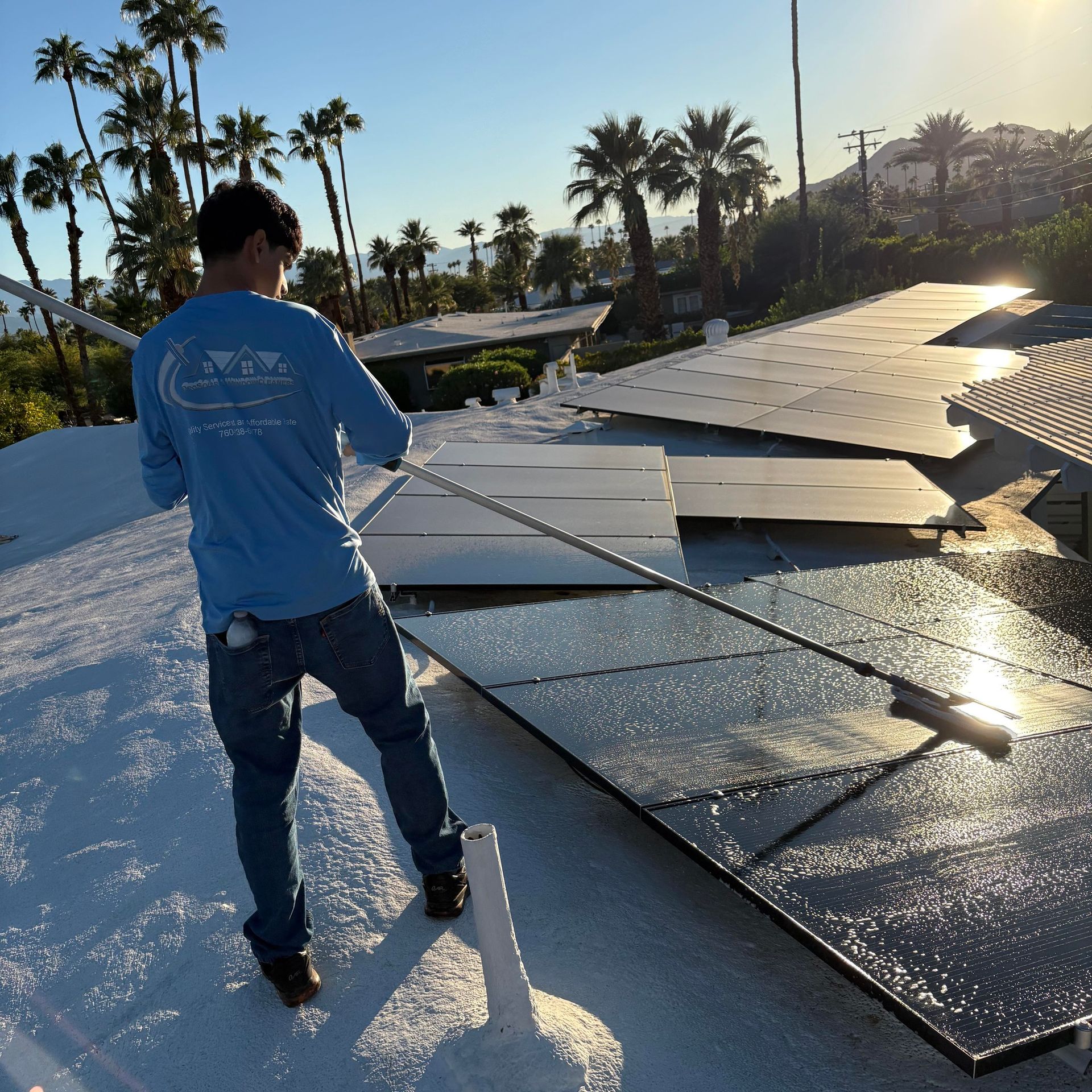Worker in blue shirt installing solar panels on a rooftop at sunset