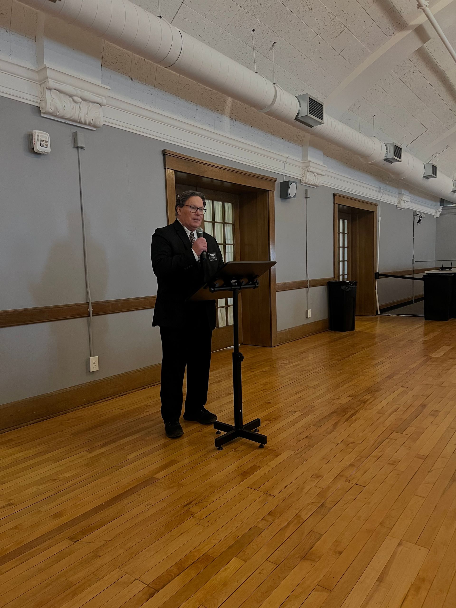 A man in a suit is standing at a podium giving a speech