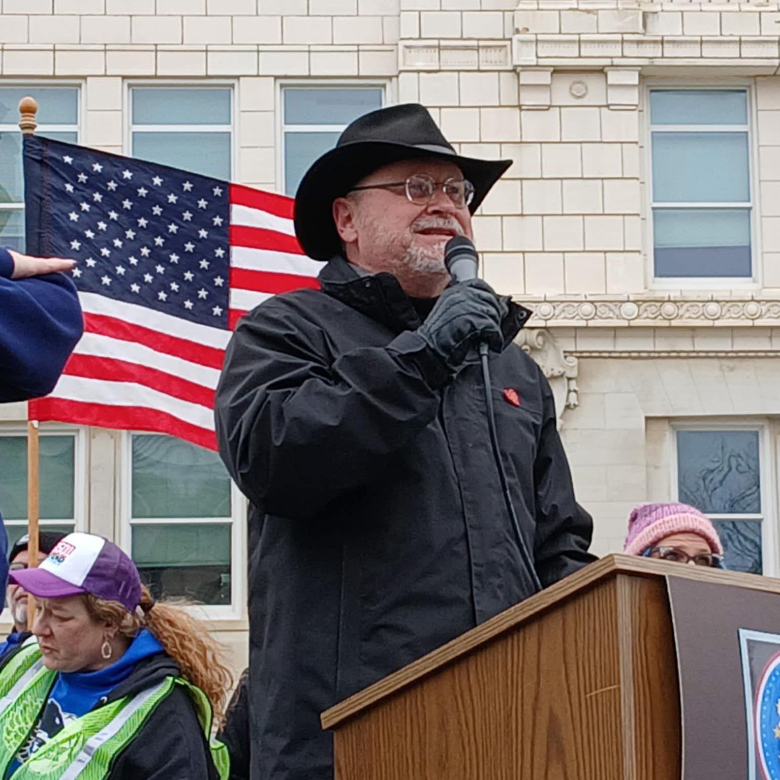 A man stands at a podium speaking into a microphone