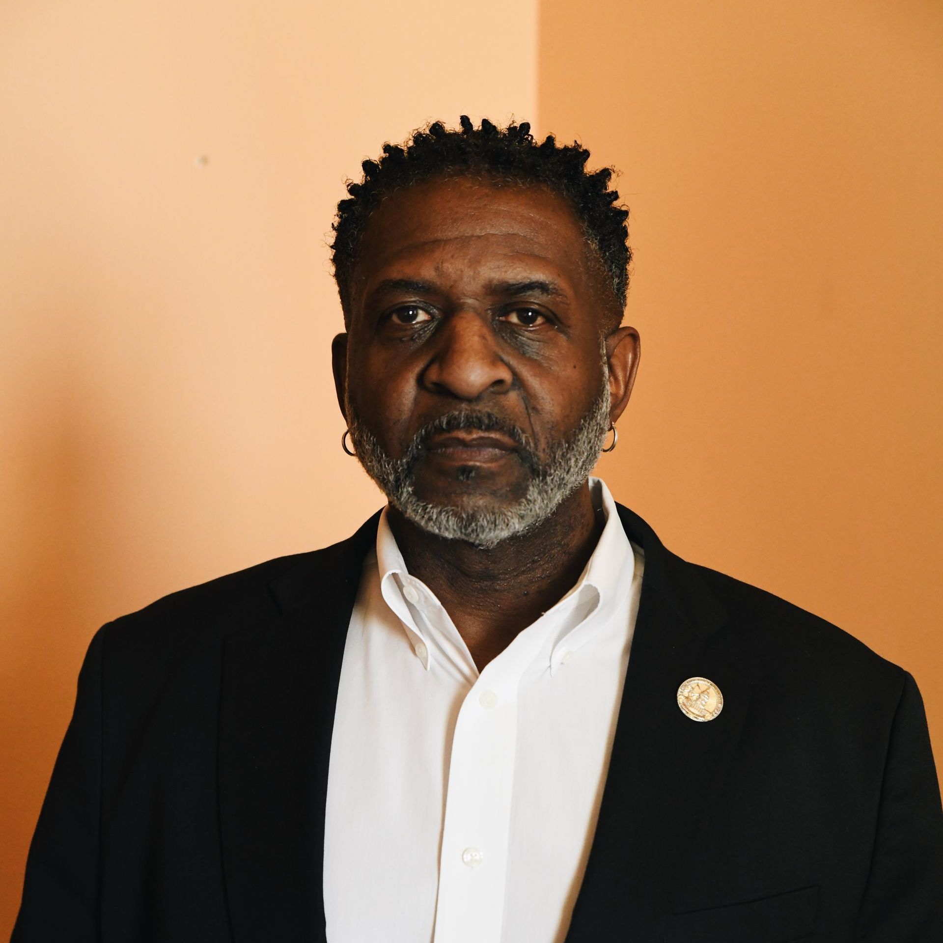 A man with a beard is wearing a black jacket and a white shirt.