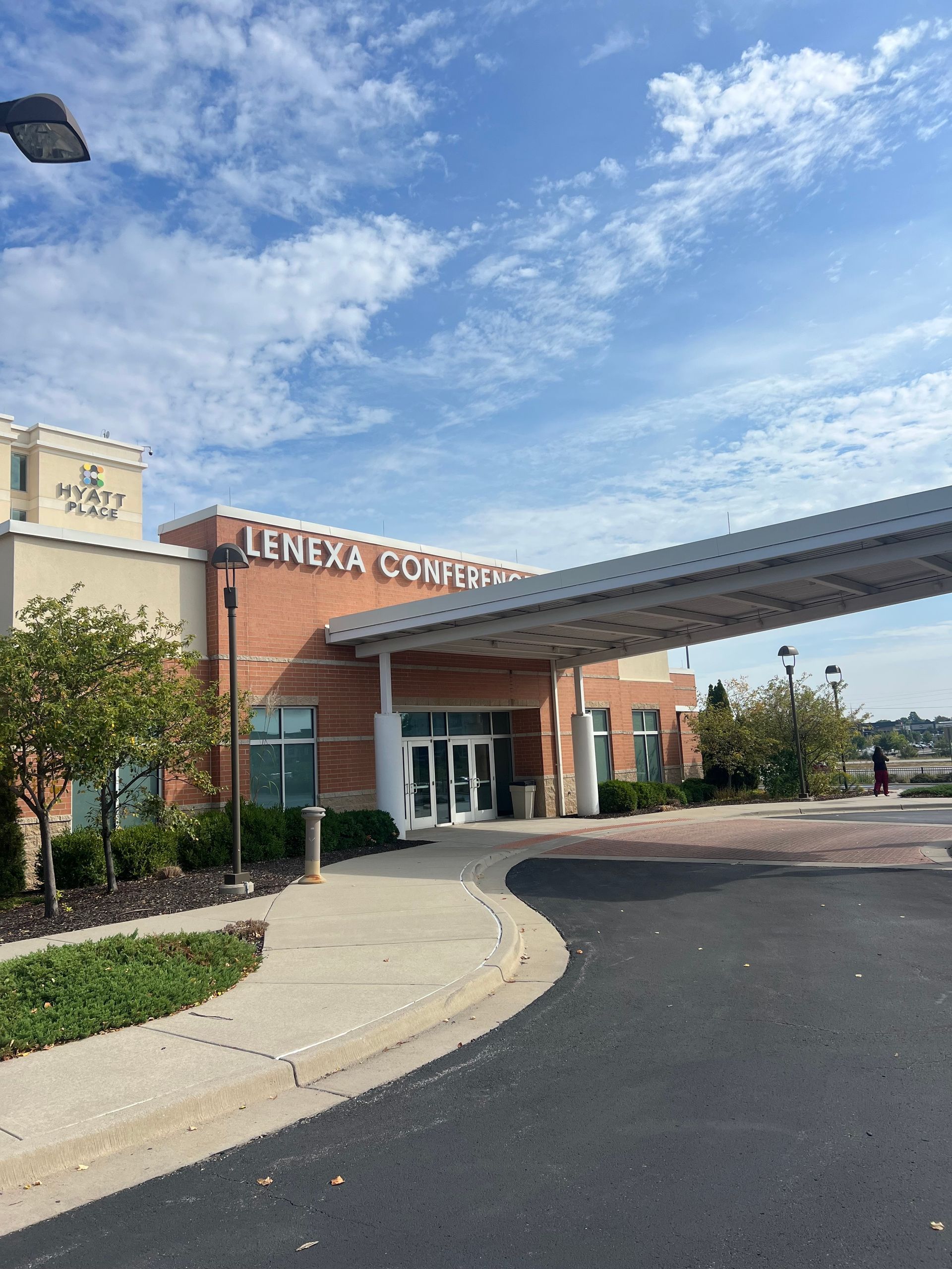 A one-story building with a covered porch, green siding, and a lit doorway at dusk.