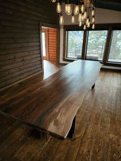A long wooden table is sitting in a room next to a window.