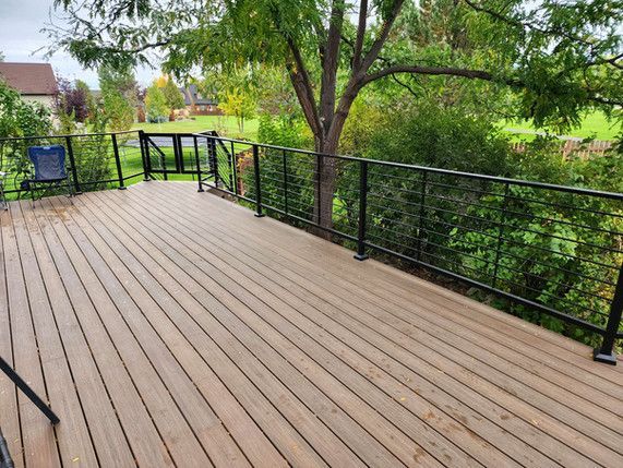 A wooden deck with a metal railing and a view of a golf course.