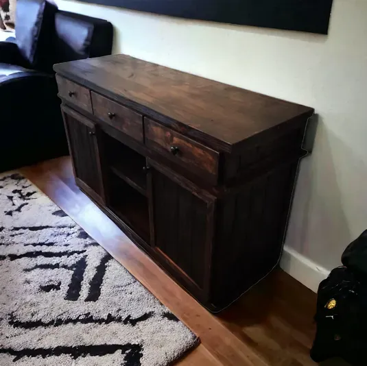 A wooden dresser in a living room next to a rug