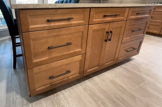 A kitchen with wooden cabinets and drawers and a granite counter top.