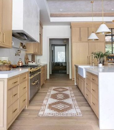 A kitchen with wooden cabinets and stainless steel appliances and a rug on the floor.