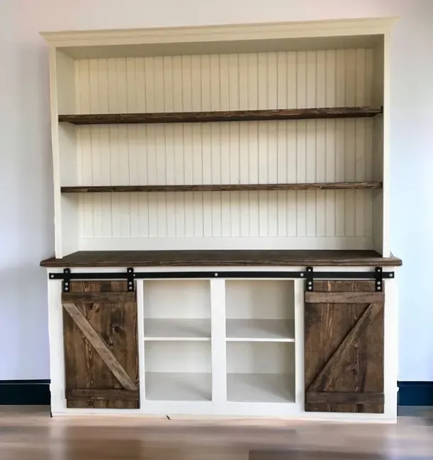 A bookshelf with sliding barn doors and shelves in a room.