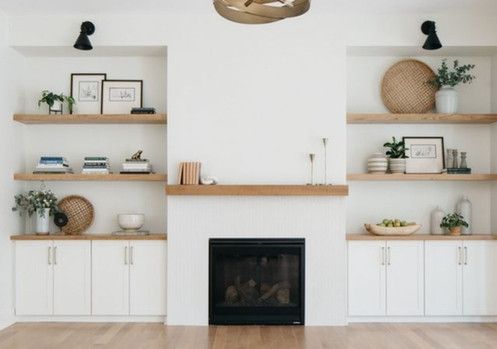 A living room with a fireplace , shelves , and cabinets.