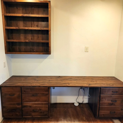 A wooden desk with drawers and a shelf above it