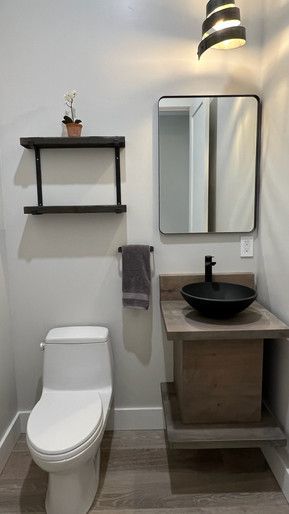 A bathroom with a toilet , sink and mirror.