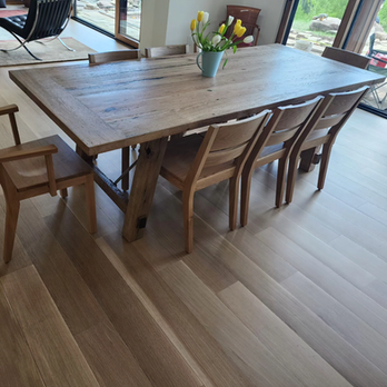 A wooden table with chairs and a vase of flowers on it