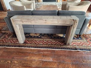 A wooden table is sitting next to a couch in a living room.