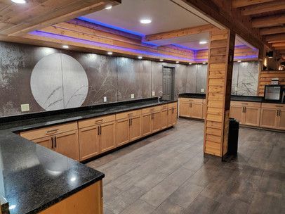 A large empty kitchen with wooden cabinets and black counter tops.