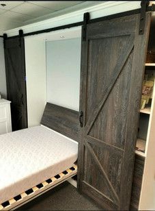 A bedroom with a bed and a sliding barn door.