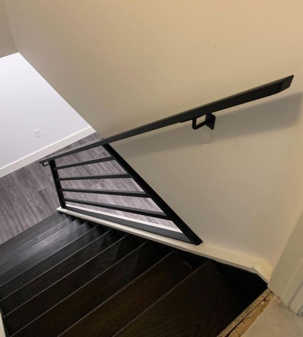 A staircase with a black railing and a white wall
