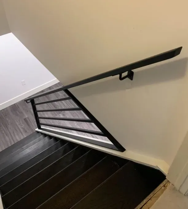 A staircase with a black railing and a white wall