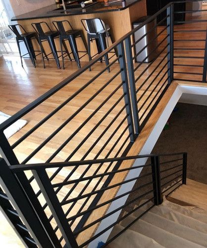 A staircase with a black railing and wooden floors