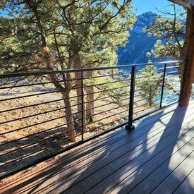 A deck with a railing overlooking a lake and trees.
