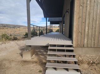A wooden deck with stairs leading up to it and a house in the background.
