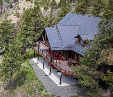 An aerial view of a large house with a large deck surrounded by trees.