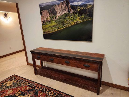 A wooden table in a room with a picture on the wall above it