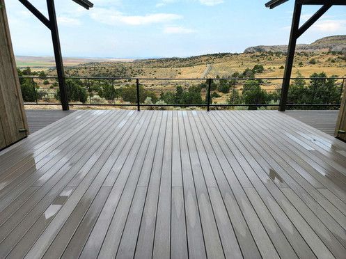 An empty wooden deck with a view of a valley.