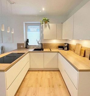 A kitchen with white cabinets and wooden counter tops.