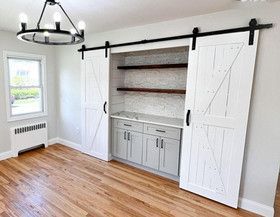 An empty room with sliding barn doors and a chandelier.