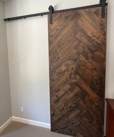 A sliding barn door with a herringbone pattern is in a room.