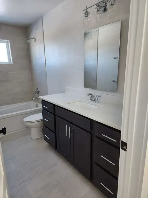 A bathroom with a toilet , sink , and mirror.
