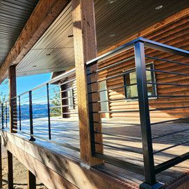 A wooden deck with a metal railing and a log cabin in the background.