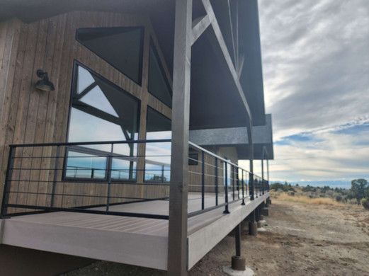 A large house with a large deck and a black railing.